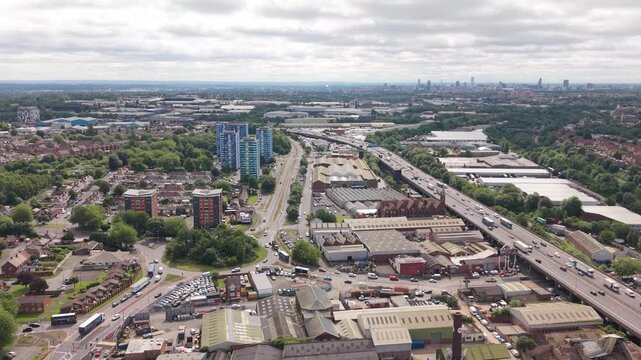 Aerial drone view of the M5 motorway running through residential neighbourhoods and industrial estates in the West Midlands, England. Urban development, logistics infrastructure and mixed land use nea