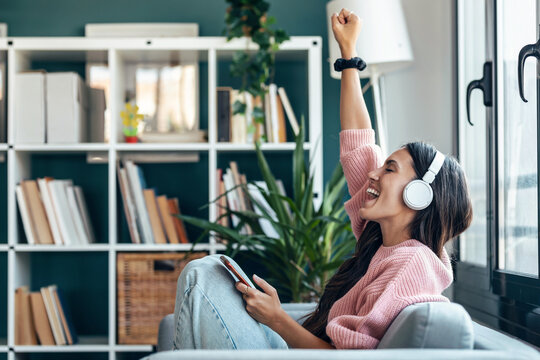 Listener enjoying music with earphone on cozy sofa at home