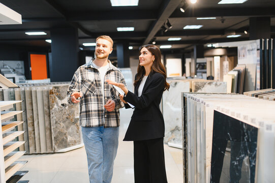 Sales assistant helping man choosing tiles in showroom
