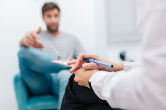 Doctor sitting with note pad while listening patient problems at office