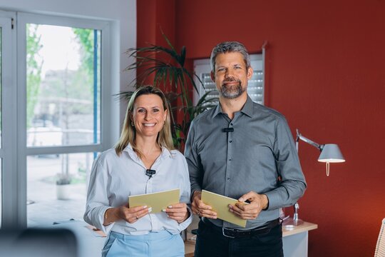 Smiling business partners with microphones in the office