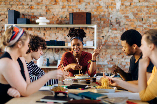 Young people sitting together at table having lunch break