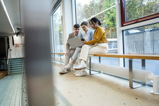 Coworking team discussing project on laptop in modern office