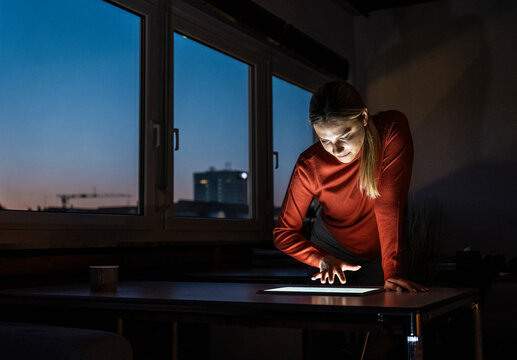 Professional working late on tablet in dark office at night