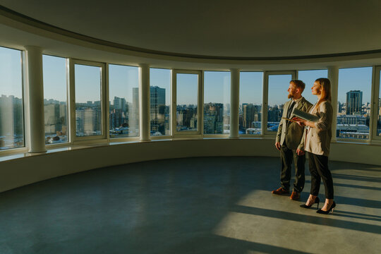 Realtors discussing real estate in empty office with urban view