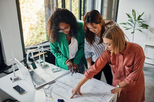 Businesswomen having a meeting in office with wind turbine models on table