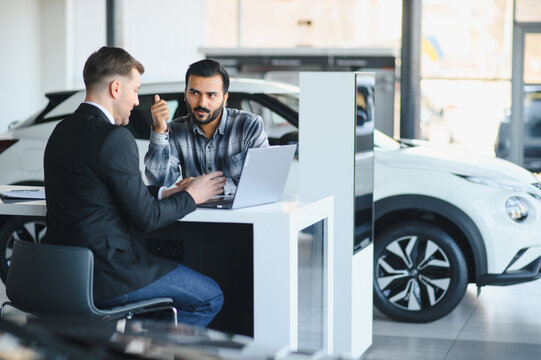 Car dealership salesman consulting customer about automobile purchase