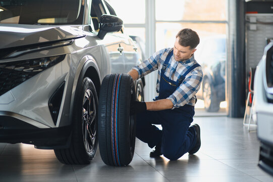 Mechanic installing new tire on vehicle in car service