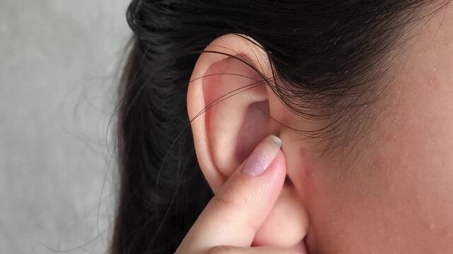 Woman hand touching earlobe before piercing procedure, ear care, healing process and personal hygiene concept.