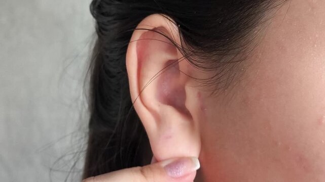 Woman hand touching earlobe before piercing procedure, ear care, healing process and personal hygiene concept.