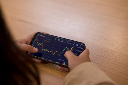 person analyzing financial stock investment market charts on a smartphone digital finance wealth management investment strategy.