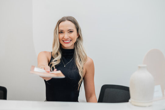 Receptionist standing behind front desk handing out a card brochure