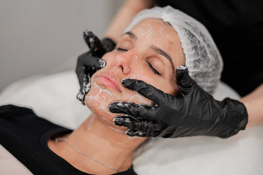 Beauty therapist massaging facial cream on clients face