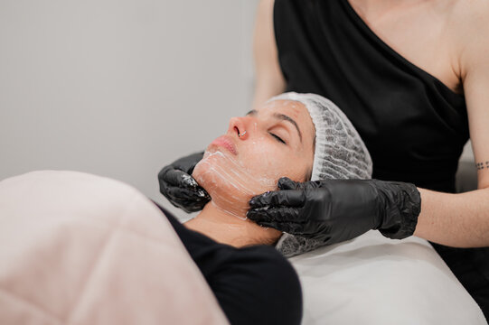 Beauty therapist massaging facial cream on clients face