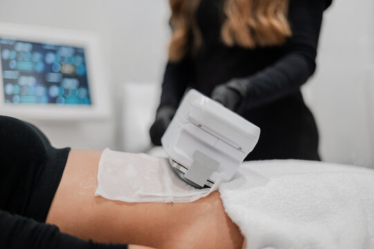 Aesthetic practitioner performing a non‑invasive body treatment on clients abdomen