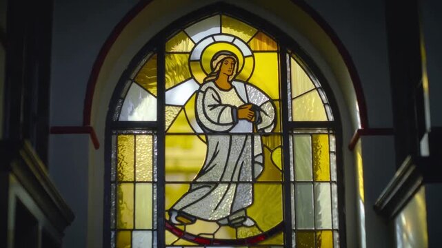 Pulling back camera revealing arched glass window in chapel over wood panel, with halo robed figure