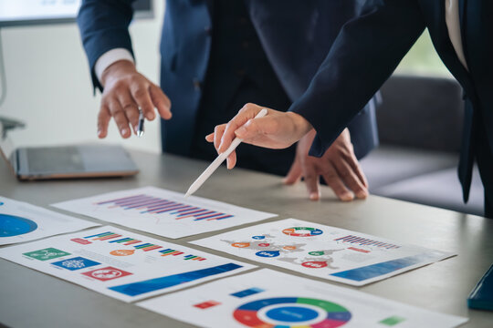 A group of business professionals conversing while looking at documents. Marketing, research, conferences, meetings, planning.
