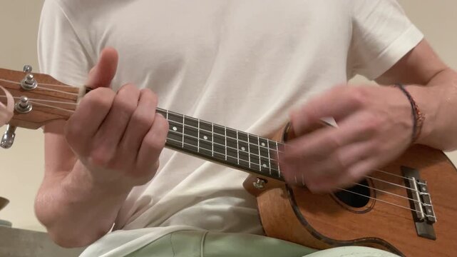 Close up of ukulele string instrument popular on Hawaii islands, teenager boy playing nylon strings during music lesson in living room, musical education and hobby art concept