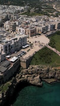 Vertical aerial view of Polignano a Mare, panorama of the Lama Monachile beach, waterfront and the buildings of the old town, Puglia, Italy
