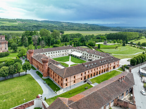 Aerial view of the University of Gastronomic Sciences campus, featuring its historic red-brick architecture, central courtyard, and surrounding green fields in Pollenzo, Piemonte, Italy.