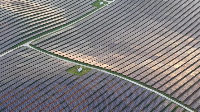 Aerial shot showing rows of photovoltaic panels and service roads in a utility-scale solar farm.