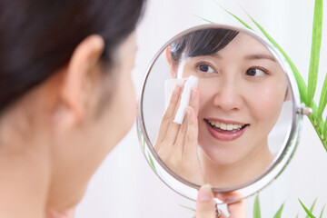 コットンで拭き取りながら肌をケアする笑顔の女性