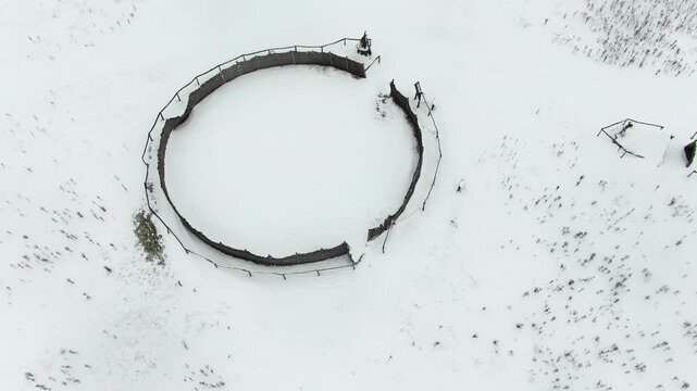 Aerial view of empty rural farm with paddocks and well covered in snow