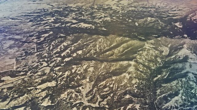 Rugged mountain folds and deeply eroded textures viewed from high altitude, aerial