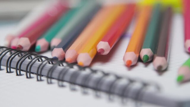 Close-Up of Colorful Colored Pencils Resting on an Exercise Book, Perfect for Back to School, School Supplies, Art Education, Creativity, and Student Learning