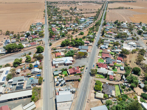 Aerial view of long straight roads and a railway line heading out of a rural town