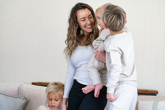 Mum carrying a baby on her hip surrounded by other sons