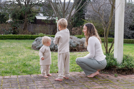 Mum with two young boys outside with a bubble stick