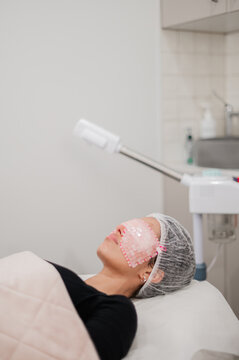 Woman lies on treatment bed with a mask covering her eyes, undergoing a skincare procedure