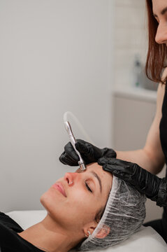 Aesthetics practitioner using a handheld device on clients face during facial treatment