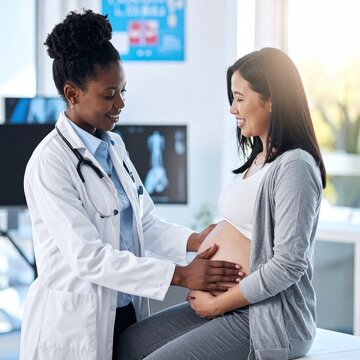 An empathetic Black doctor gently examines the belly of a happy pregnant Asian woman in a modern clinic, evoking comfort, trust, and professional prenatal healthcare support.