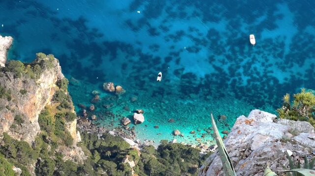 High Angle View of Secluded Rocky Cove with Transparent Water, Shadow Patterns on Seabed and Boats Capri Island Italy Summer