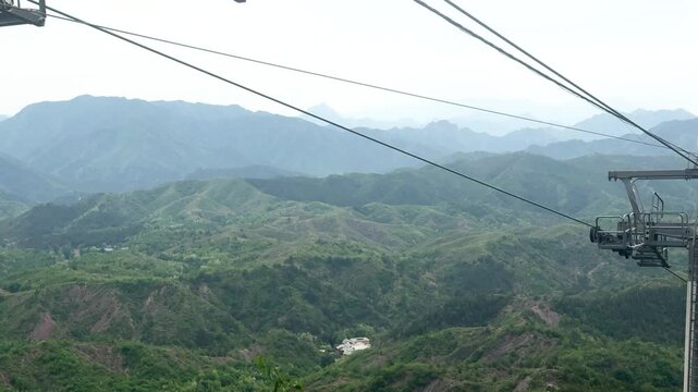 Cable car moving above lush green mountain forest. Aerial transportation for tourists visiting mountain resort. Scenic travel experience in nature, outdoor adventure and sightseeing.