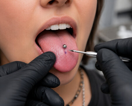 Professional piercing artist marking tongue for piercing procedure