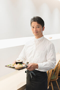 和食ランチプレートを持つ40代男性カフェ店員