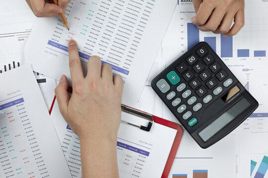 Business team analyzing financial report with calculator on desk. Concept of accounting audit, data analysis, budgeting investment, tax planning, and corporate wealth management.