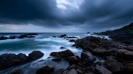 Fototapeta premium A calm rocky shoreline is viewed beneath dramatic swirling storm clouds creating a powerful and lasting natural impression