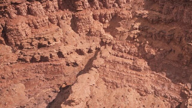 The scene shows a dry and rugged landscape with large rock formations. The ground is mostly bare with some small stones scattered around. This is a remote location with no signs of vegetation.