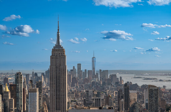 New york, usa august 21,2024. New york city skyline featuring empire state building and one world trade center against a bright blue sky with clouds