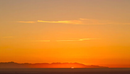 Fototapeta premium A fiery sky during sunset, with dark land silhouettes, painted in shades of orange