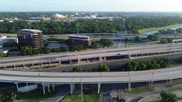 Complex highway systems, elevated train tracks dominate horizon behind S University Dr commercial sites. Morning light emphasizes linear roadway patterns, wooded buffer zones, Fort Worth, Texas
