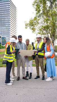 Diverse team of architects and engineers collaborating, reviewing construction plans, and planning urban development outdoors