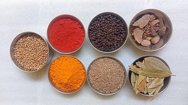  Top view of traditional Indian spices in steel bowls on white background