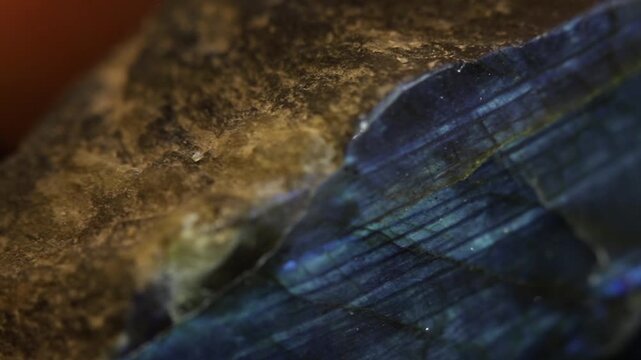 Labradorite mineral close up on video. Macro shot. Collectible mineral stone on black background. Changing colors, shifting lights and reflections. Examining in hand