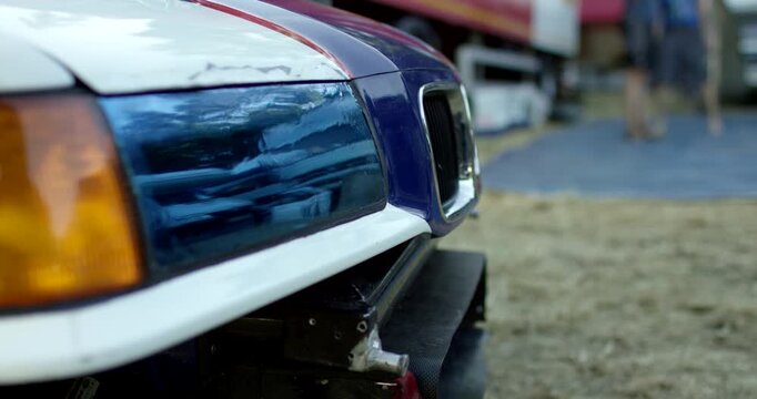 Close-up profile view of the front headlights and grille of a white sports car with racing stripes