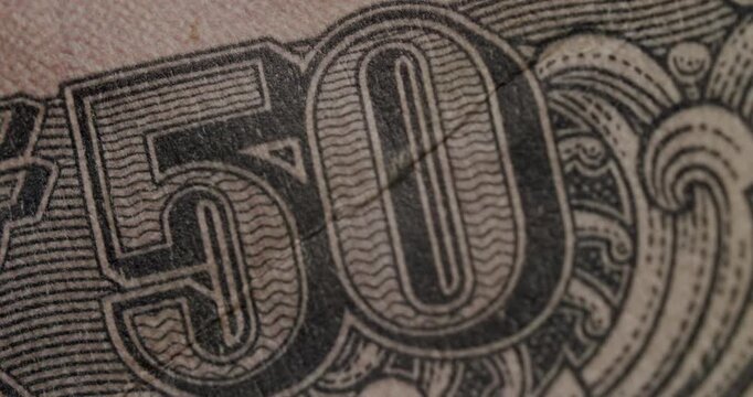 Extreme close-up of a fifty Indian rupee banknote, showing the portrait of Mahatma Gandhi and other intricate details of the currency, representing India's economy and financial system